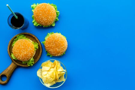 USA cuisine. Burger, chips and drink for national American kitchen concept on blue background top view mock upの写真素材