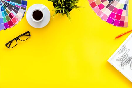 Illustrator, artist tools concept. Work space of designer with instruments, pallet, pencil, glasses and coffee on yellow background top view space for textの写真素材