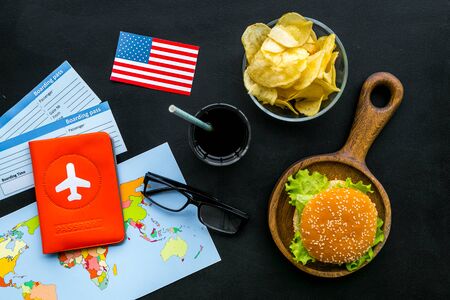 Traditional food. Burger, map, tickets, passport and USA flag for gastronomical tourism to America on black background top viewの写真素材