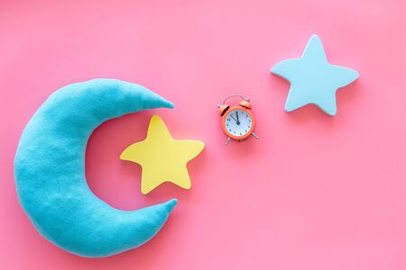 Insomnia concept. Night sleep concept with moon, stars toys and alarm clock on pink background top viewの写真素材