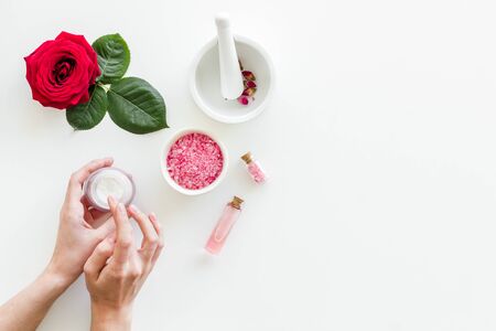 Body care and treatment. Cream in hands, bath salt, lotion for organic cosmetics with rose flower on white background top view space for textの写真素材