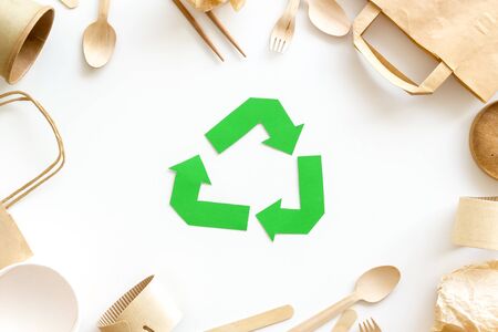 Green paper recycling sign with waste materials paper, bag, cup, wooden flatware, spoon, fork on white background top viewの写真素材