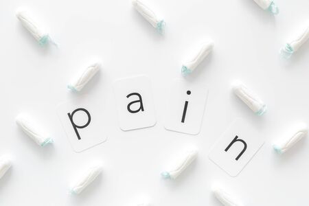 Gynaecologist and menstruation concept with tampons and pain word pattern on white background top viewの写真素材