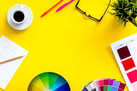 Designer work space with pallet, glasses, pencils and coffee on yellow background top view mockupの写真素材