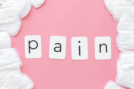 Gynaecologist. Woman hygiene and menstrual period concept with sanitary pads and pain word on pink background top viewの写真素材