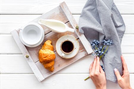 Breakfast in bed with croissant, coffee in cup with milk on tray on white wooden background top viewの写真素材