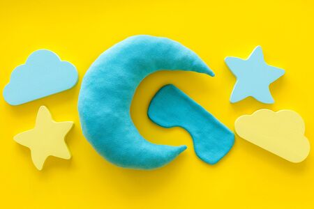 Good dreams. Night sleep concept with moon, clouds, stars toys and blindfold on yellow background top viewの写真素材