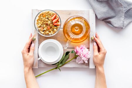 Homemade breakfast in bed with granola, tea and fruit on tray on white background top viewの写真素材