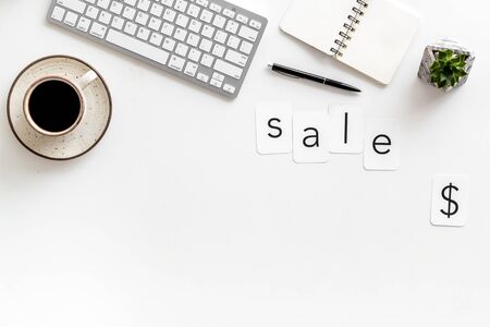 Sale word , dollar sign, keyboard, notebook, coffee on white office desk background top view copyspaceの写真素材