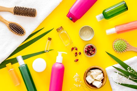 Cosmetic for hair treatment with shampoo, conditioner, styling, oil, comb on yellow background top view patternの写真素材