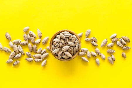 Almond in bowl on yellow background top view