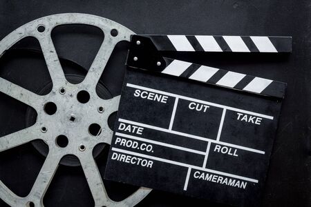 Movie premiere concept. Watch film in cinema with video tape and clapperboard on black background top viewの写真素材