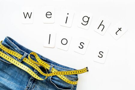 Diet, fitness and body shape. Trousers with measuring tape and weight loss concept for sport concept on white background top viewの写真素材
