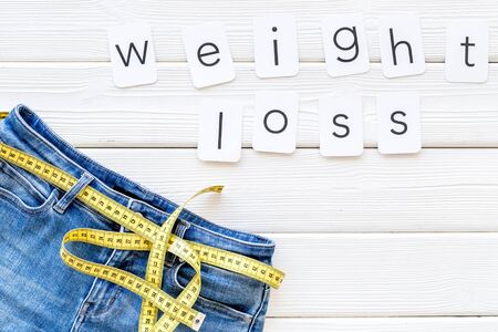 Weight loss text with jeans and measuring tape on white wooden background top viewの写真素材