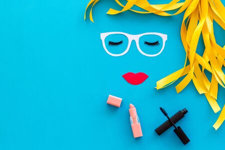 Visagiste or stylist job. Decorative cosmetic for make up with face model, mascara and lipstick on blue background top view mock upの写真素材