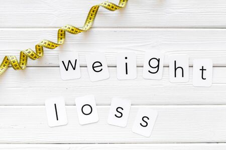 Measuring tape and weight loss concept for sport concept on white wooden background top viewの写真素材