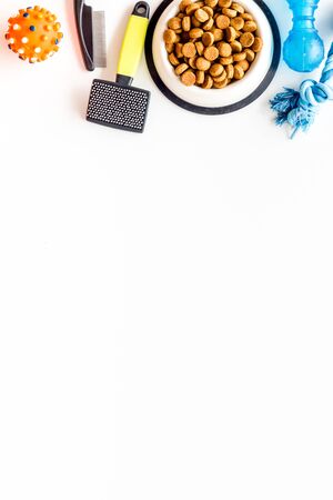 Dry pet food in bowls and grooming tools on white background top view space for textの写真素材