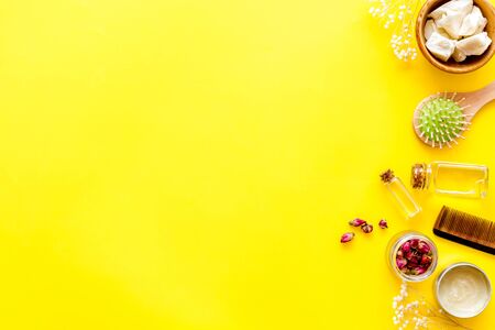 Bottle with jojoba, argan or coconut oil, styling, comb for hair style on yellow background top view mock upの写真素材
