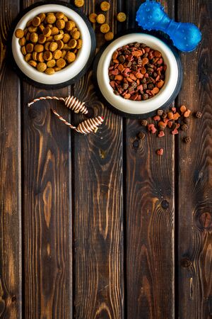 Dry pet food in bowls and toys on wooden background top view space for textの写真素材