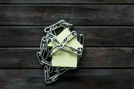 Protection. House security system with figure and chain on wooden background top view