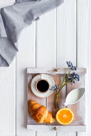 Homemade breakfast on the tray with cup of coffee with cream and fruit on white wooden background top viewの写真素材
