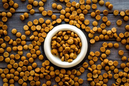 Puppy and kitten care. Dry pet food in bowl on wooden background top view patternの写真素材