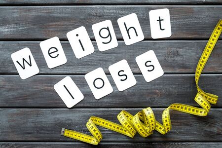 Diet, fitness and body shape. Measuring tape and weight loss concept for sport concept on wooden background top viewの写真素材