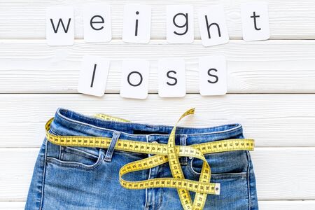 Trousers with measuring tape and weight loss concept for sport concept on white wooden background top viewの写真素材