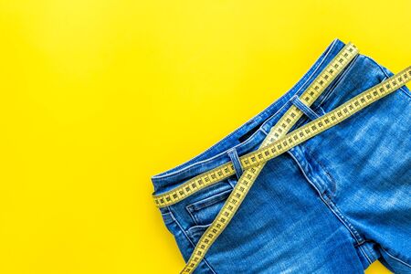 Trousers with measuring tape for weight loss and sport concept on yellow background top view space for textの写真素材