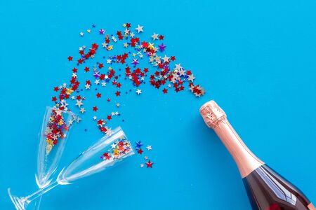 Champagne bottle with glasses and colorful party streamers for celebration on blue background top viewの写真素材