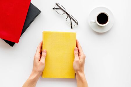 Book in hands for reading and education with coffee and glasses on white background flat layの写真素材