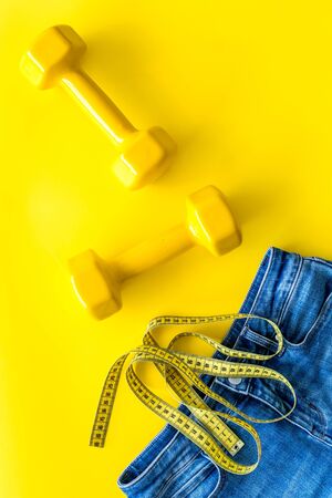 Weight loss concept with jeans, bars and measuring tape on yellow background top viewの写真素材