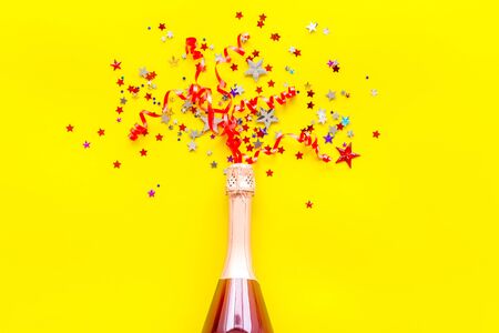 Party with champagne bottle and colorful party streamers on yellow background top viewの写真素材