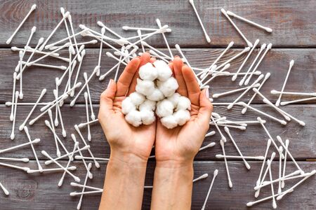 pattern of cosmetic cotton swabs and cotton in hands on wooden background top viewの写真素材