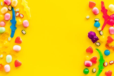 Sweets pattern with dots and marmalade frame on yellow background top view copy space.