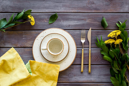 Table setting with plates, flatware and flower on wooden background top view