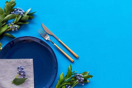 Table setting with plates, flatware and flower on blue background top view copy spaceの写真素材