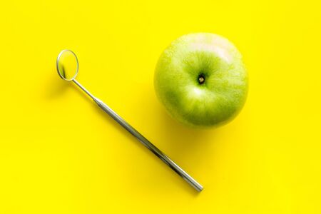 Dentist work desk with mirror and apple on yellow background top viewの写真素材