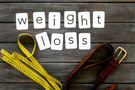 weight loss text with belt and measuring tape on wooden background top viewの写真素材