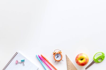 Back to school with stationary, notebook and alarm clock on white student desk background top view mock-upの写真素材