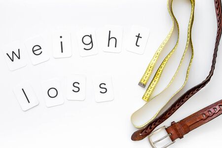 weight loss text with belt and measuring tape on white background top viewの写真素材