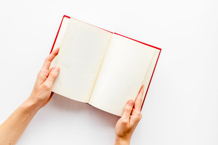 Book in hands for reading on white library desk background top view space for text