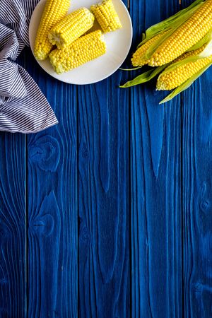 Corn on cobs and on plate on blue wooden background top view copy space
