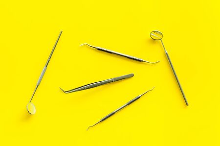 Dentist work desk with tools for teeth on yellow background top viewの写真素材