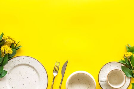 Table setting with plates and flatware on yellow background top view mock upの写真素材