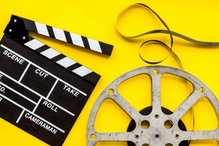 Filmmaker profession with clapperboard and video tape on yellow background top viewの写真素材