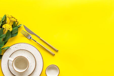 Elegant table setting with plates and tableware on yellow background top view mock-upの写真素材