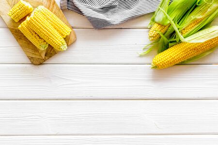 Corn on cobs on white wooden background top view copyspace