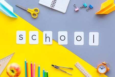 Creative mess on students desk with school copy on yellow and gray background top viewの写真素材