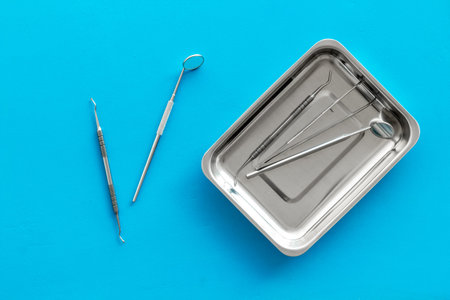 Dentist work desk with tools for teeth on blue background top view